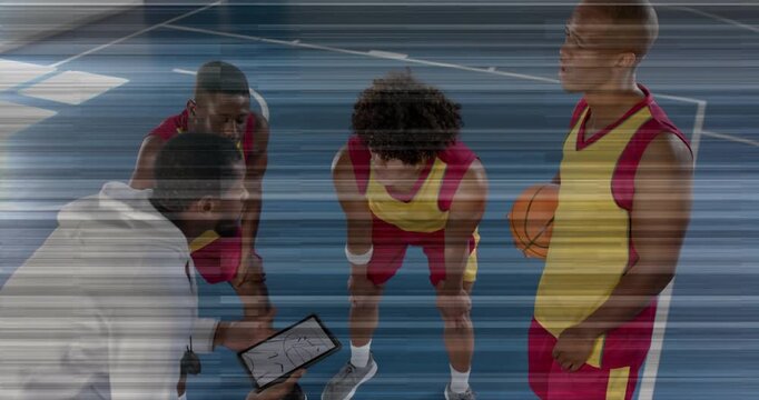 Coach crouching before three players in sports coaching huddle, tapping tablet diagram guiding play