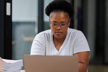 Overworked African American business woman or female office worker suffering from neck pain after had a long day at work, massaging her neck. office syndrome concept

