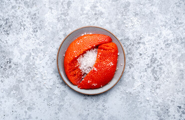 Fresh whole raw red caviar extracted from live trout or salmon with sea salt, grey background, top view