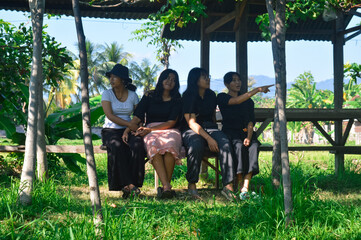 Seated calmly in a quiet grapevine shelter, four girls observe their surroundings, embracing the...
