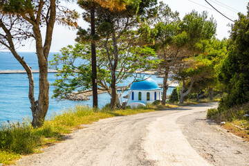 Agios Kirykos coast and road view to Church of Analipsi The Ascension Greek christian orthodox religion at Therma, Ikaria island, Greece blue zone
