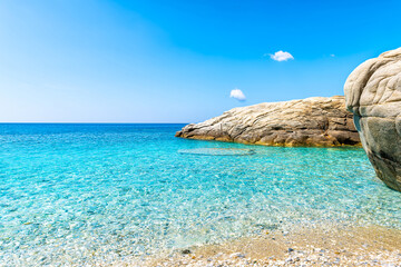 Seychelles beach at Magganitis, Ikaria island Greece by Icarian sea with crystal clear green turquoise water by boulder rocks cove