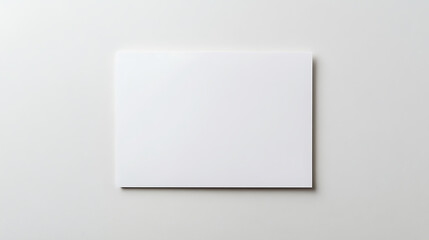 Minimalist white card laying flat against a bright white background, emphasizing simplicity and clean design with a focus on space and shadow.