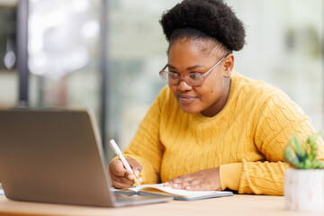 Busy African American business woman using laptop working in corporate executive at office. professional female company hr or bank manager looking at computer.
