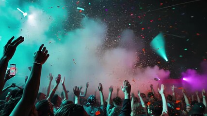 Exciting crowd celebration with colorful confetti and vibrant lights at a music event in a lively venue - Powered by Adobe