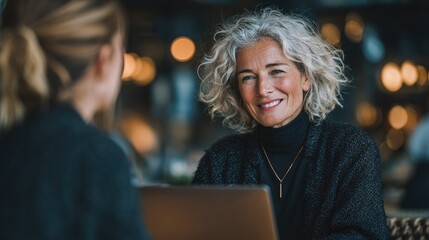 Professional ladies employee and manager having conversation using laptop at work