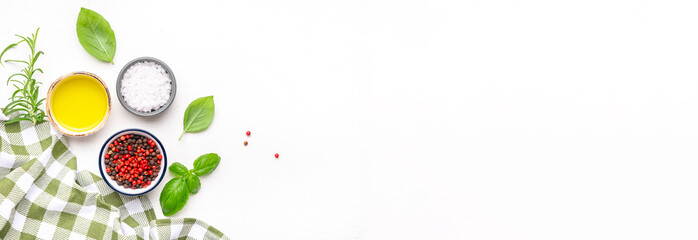 Food and cooking background, spices and herbs, top view. Rose and black pepper, fresh rosemary, basil, olive oil and sea salt on white table