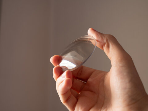 hand holding round lens for eyeglass