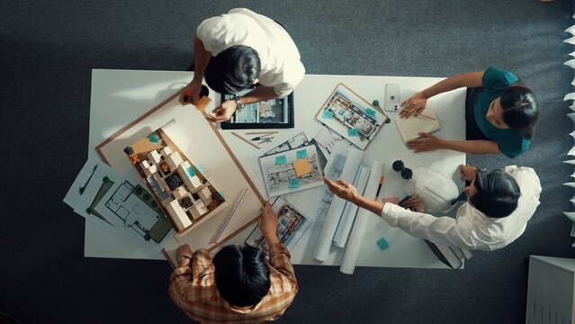 Top down aerial view of architect engineer team writing sticky notes and sticking note at house model while interior designer talking and discussing about building exterior designing. Alimentation.