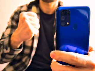 Angry man using blue phone and clenching fist