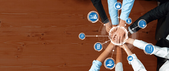 A dynamic overhead view of diverse hands coming together on a wooden table, symbolizing...