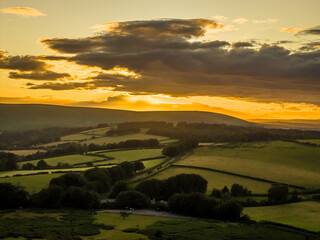 Family hiking on Dartmoor tors at sunset, silhouetted against dramatic skies in scenic moorland...