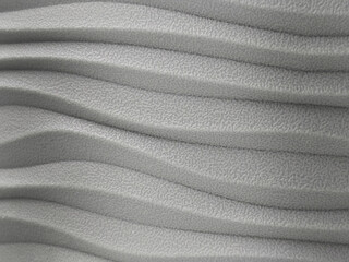 Abstract gray surface with wave pattern and textured finish. Close-up of modern design element or decorative background. Minimalist and industrial style.

