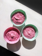 Three blueberry pink muffins stand in the center, framed by strips of light. The pink and purple...