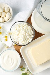 Fresh dairy products and flowers on white wooden table, flat lay