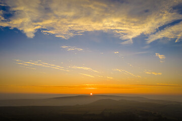 Family hiking on Dartmoor tors at sunset, silhouetted against dramatic skies in scenic moorland landscape