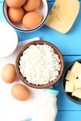 Different dairy products and eggs on light blue wooden table, flat lay
