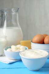 Different dairy products and eggs on light blue wooden table, closeup