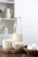 Different dairy products and eggs on gray textured table in kitchen