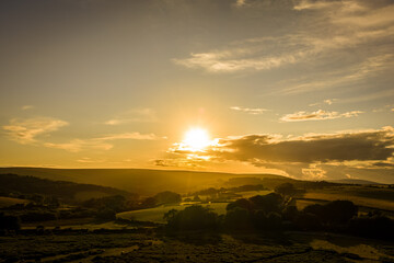 Family hiking on Dartmoor tors at sunset, silhouetted against dramatic skies in scenic moorland landscape