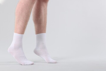 Man wearing clean white socks on light background, closeup. Space for text
