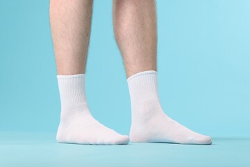 Man wearing clean white socks on light blue background, closeup