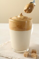 Taking cream from delicious dalgona coffee and brown sugar at light table, closeup