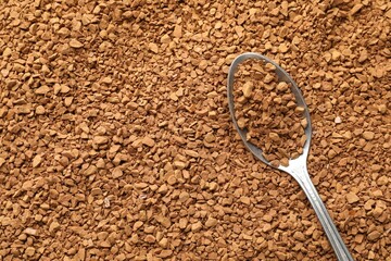Spoon with aromatic instant coffee as background, closeup