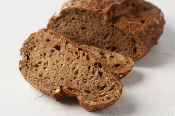 Pieces of fresh rye bread on white textured table, closeup