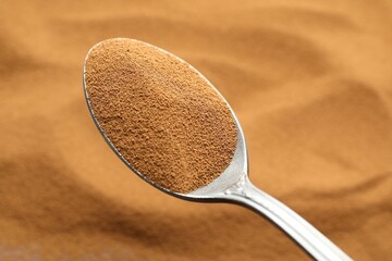 Spoon with aromatic instant coffee as background, closeup