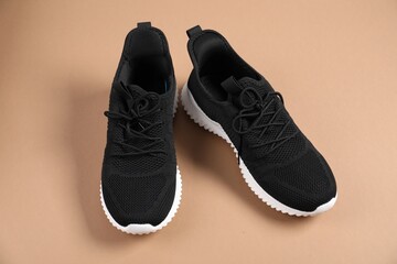 Pair of black sneakers on beige background
