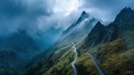 Overhead drone shot of a winding mountain pass scenic landscape with fog drifting between the peaks