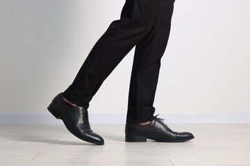 Man wearing pair of black leather shoes indoors, closeup
