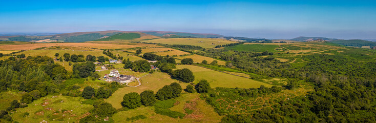 Sunrise over a house nestled between rocky tors in Dartmoor, with warm light illuminating the...