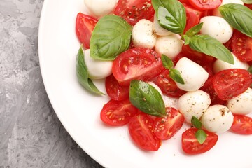 Tasty salad Caprese with mozzarella, tomatoes, basil and spices on grey table, top view