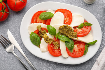 Tasty salad Caprese served with pesto sauce on grey table, flat lay