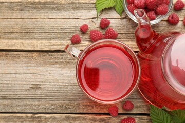 Tasty raspberry tea, berries and leaves on wooden table, flat lay. Space for text