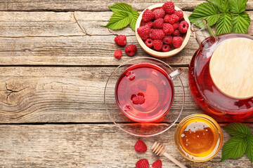 Tasty raspberry tea, berries and leaves on wooden table, flat lay. Space for text