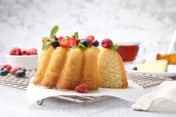 Tasty Bundt cake with berries, honey and mint on light grey table, closeup