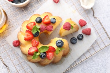 Tasty Bundt cake with berries, honey and mint on light grey table, flat lay
