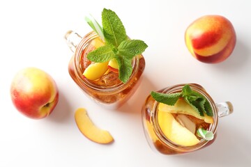 Refreshing iced peach tea with mint in mason jars and fresh fruits on white table, flat lay