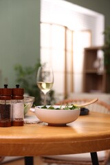 Bowl of salad, white wine and spices on table indoors