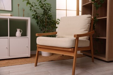 Stylish armchair near shelving unit and houseplant indoors