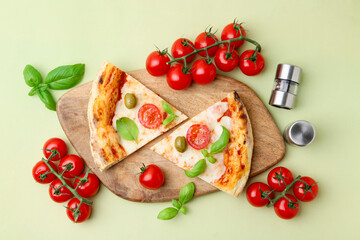 Pieces of delicious pizza, tomatoes and basil on light green background, flat lay