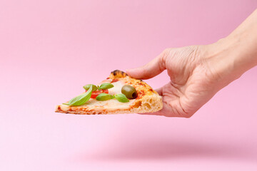 Woman holding slice of delicious pizza on pink background, closeup