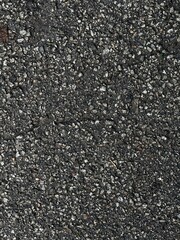 Close-up macro shot of grey asphalt texture. Rough and detailed stone surface, ideal for use in backgrounds, construction themes, or design mockups