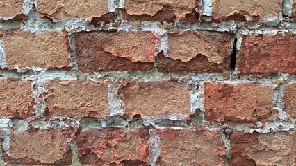 Close-up of weathered red brick wall with textured surface and crumbling mortar