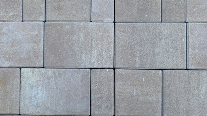 Uniform brown square concrete paver blocks arranged in seamless pattern