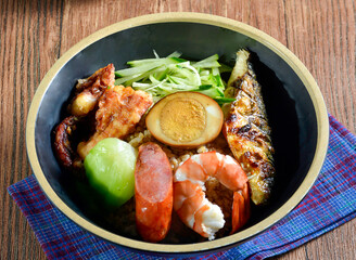 Seafood rice bowl with grilled fish, shrimp and assorted ingredients in bowl side view of Asian food