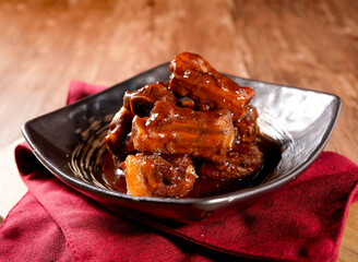 Braised pork spare ribs in a rich, savory glaze in plate side view of Asian dish